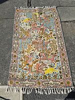 Full view of the rectangular embroidered tapestry on ground showing composition and border with text.