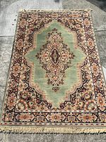 Full top view of rectangular machine woven rug displayed on a concrete floor with visible pattern and fringed edges.