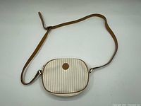 Full front view of the small Fendi crossbody bag with beige and white vertical stripes and brown leather strap.
