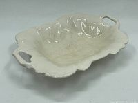 Angled view of the off-white porcelain serving dish showing shape, handles, and interior condition.