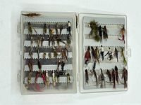 Top view of two sections of the plastic case showing an assortment of different vintage fly fishing jigs organized neatly in foam slots.