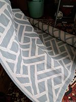 Image of the woven mat partially rolled showing the geometric pattern in light blue and white.