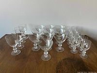 25 clear stemmed glasses arranged on wooden table