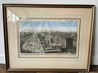 Framed cityscape print under glass showing architectural scene with gardens, fountains, and distant city skyline under a blue sky.