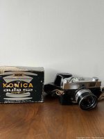 Photo showing Konica Auto 52 camera with Hexanon 1:2.8 lens next to original branded box.