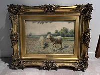 Front view of ornate gilt carved frame with sheep landscape painting visible