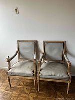 Front view of both chairs showing carved frames and upholstery wear