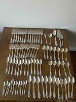 Overhead view of silverware laid out on wooden table including forks, spoons, and serving pieces