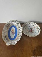 Photo of two pieces from the Schumann Bavaria Dresden Line china set showing their floral motifs, pierced lattice borders, and gold rim detailing.