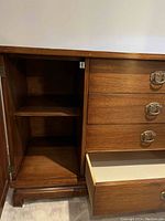Open cabinet door showing interior shelf of wooden dresser.