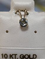 Front view of 10K gold pendant holding a round aquamarine gemstone on display card.