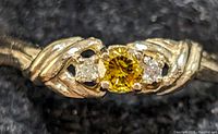 Front view of ring showing yellow center diamond and clear side diamonds