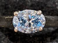 Face-on close-up of oval-cut diamond in four-prong setting on white gold band