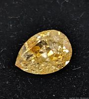 Loose pear-shaped yellow diamond on black background