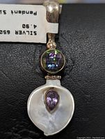 Front view of sterling silver pendant featuring marcasite, round faceted multicolor gemstone, pear-shaped amethyst on mother of pearl shell.