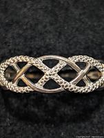 Close-up front view of the sterling silver openwork ring showing textured and smooth intersecting bands forming an oval lattice design.