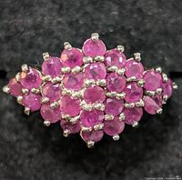 Close-up front view of sterling silver ring featuring a cluster of faceted round rubies.