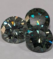 Close up of three round cut moissanite gemstones showing their brilliant sparkle and faceting.