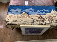 Full view of tablecloth showing sky, mosque, desert ground, and camel caravan with figures