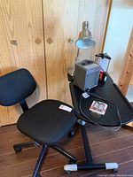 Wide view showing the black office chair, adjustable table lamp, portable heater, and Energizer LED lamp on a black base.