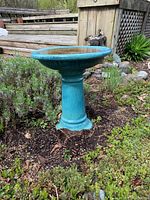 Full view of the blue ceramic bird bath placed outdoors in a garden setting showing the entire piece.