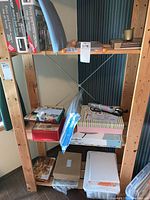 Wide view of shelf with various crafting supplies including boxes, paper cutter, glue gun, and materials organized on shelves.