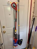 Photo showing the mop with red handle, gray mop head, a cleaning tool with blue handle, and a red dustpan.