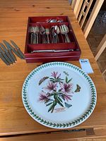 Photo showing Oneida flatware set in wooden box on wooden table, with a large ceramic platter in front