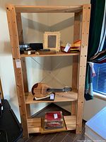 Front view of a solid wood shelving unit with multiple items on shelves, highlighting the structure and dimensions.