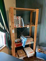 Front view of the solid wood shelving unit showing three shelves with various items placed on and around it for scale.
