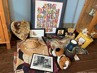 Full lot image showing various teddy bear throws, stuffed animals, framed artwork, keepsake containers, and decorative items arranged on floor and furniture.