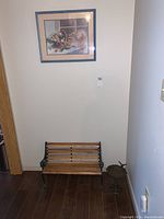 View of small wooden bench with cast iron frame and ornamental bird bath on the right