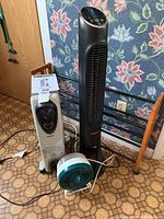 Full view of three appliances: white Omni Max oil-filled heater, tall black tower fan, small white and turquoise fan.
