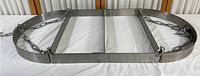 Metal rectangular pan/pot holder frame with two hanging chains laid on surface.