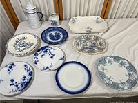 Overview of all items laid out on a cloth surface showing the variety of plates, platter, jug, and creamer cup.