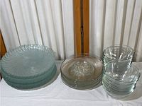 Set of clear glass plates and bowls arranged in stacks showing different patterns and sizes.
