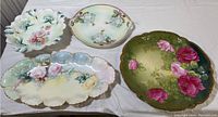 Four flower themed porcelain dishes on white cloth background