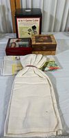 Photo showing 6 in 1 game cube, two wooden trinket boxes, several towels/cloths arranged on white surface