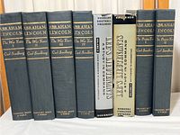 Front view showing all nine books standing upright, six Abraham Lincoln volumes in blue covers by Carl Sandburg and three Lee's Lieutenants books by Douglas Southall Freeman, two with dust jackets.
