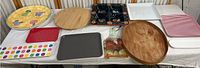 Table display of platters and trays including wooden, plastic, ceramic, and a painted rooster planter