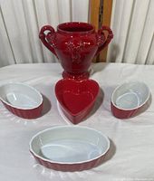 Overview of the lot showing the red ceramic vase, heart-shaped dish, and three small oval dishes arranged on a white surface.