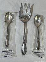 Full view of three pieces of flatware: one large serving fork (9 inches) and two small spoons (6 inches) in plastic wrapping, showing overall condition and packaging.