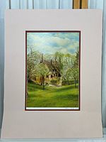 Full view of the framed signed print featuring a house with surrounding trees and grass.