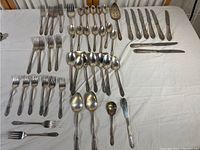 Full spread of flatware arranged on table showing forks, spoons, knives, and serving pieces