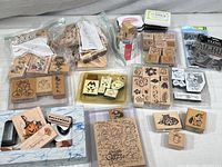 Full assortment of wooden rubber stamps, some in plastic bags, with ink pads included. Visible designs include pumpkins, hearts, flowers, animals, and script words.