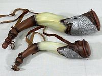 Both horn-shaped decorative powder holders laid side by side showing full size and leather straps.