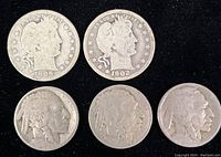 Obverse side of two Barber silver quarters dated 1906 and 1902, and obverse side of three Buffalo nickels, all heavily worn with no visible dates on nickels.