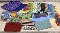 Assorted quilting fabric pieces with various prints and colors displayed flat in front of the bin.