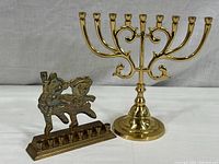 Both menorahs placed side by side on a white surface showing the relative size difference and style contrast.