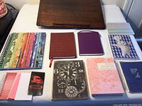 Photo showing 10 blank journals and notebooks of various sizes and designs arranged on a surface.